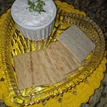 Foto da receita de Patê de Peito de Peru. Observa-se um recipiente transparente com 4 torradas em cima e, ao lado, um potinho com o patê.