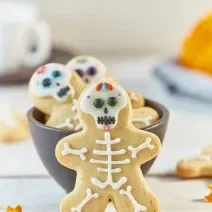 Imagem aproximada de um biscoito em formato de caveira com a decoração no tema de halloween, em uma bancada em tons claros