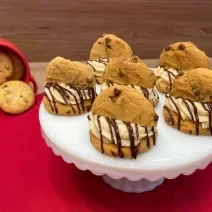 Fotografia mostra cookies cobertos por um creme branco e chocolate derretido, e meio cookie no topo.