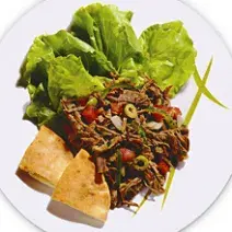 foto tirada de um prato branco redondo com carne desfiada e folhas de alface.