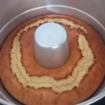 Foto da receita de Bolo de Arroz Cru. Observa-se um bolo assado ainda dentro de uma forma com furo no meio