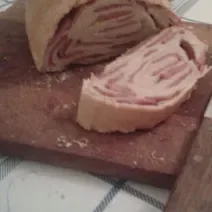 Foto da receita de pão de linguiça tartano servida em duas porções grandes cortadas ao meio sobre uma tábua de madeira