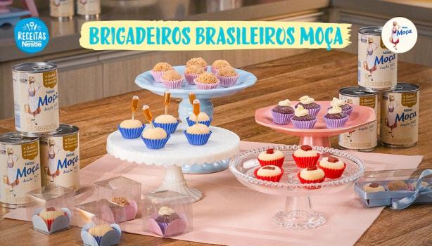 Fotografia mostra quatro tipos de brigadeiros dispostos sobre uma mesa de madeira.