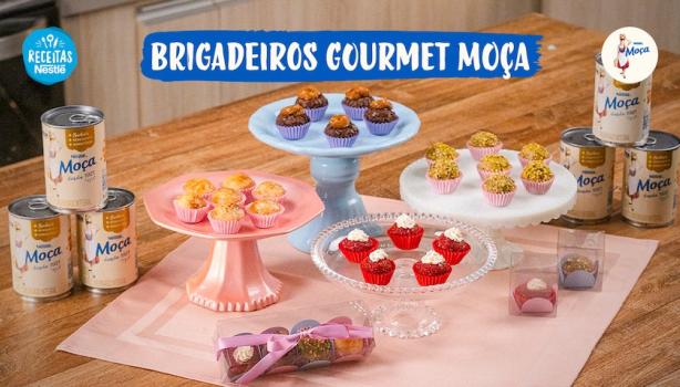 Fotografia mostra quatro tipos de brigadeiros dispostos sobre uma mesa de madeira.