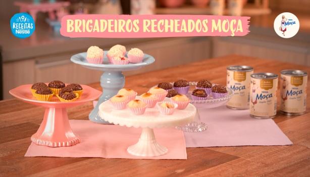 Fotografia mostra quatro tipos de brigadeiros dispostos sobre uma mesa de madeira.