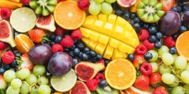 26 frutas ricas em fibras para você conhecer Imagem de frutas variadas como laranja, manga, uvas, kiwi, morangos.