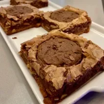 Fotografia mostra um brownie de chocolate com um cookie de chocolate em cima.