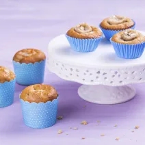 Foto de 6 cupcakes em forminhas azuis. 3 destes estão em uma mesinha branca e 3 estão ao lado da mesinha