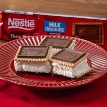 Fotografia em tons de vermelho com um prato vermelho ao centro. Em cima do prato existe 3 biscoitos Choco Biscuit recheados com sorvete de creme.