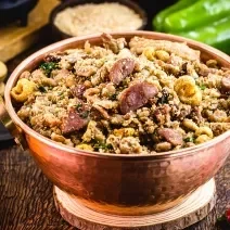 Receita de Feijão Tropeiro de Natal, tradicional e delicioso, feito com feijão, lombinho, bacon, linguiça calabresa e pimenta, servido em uma panela de cobre sobre uma mesa de madeira com diversos ingredientes in natura