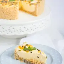 fotografia em tons de branco e amarelo tirada de uma torta com uma fatia retirada, à frente um prato redondo com a fatia de torta e um garfo para servir.