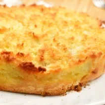 imagem de uma torta dourada com a superfície crocante e levemente tostada, sobre um prato branco