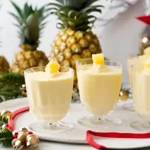 Receita de Delícia Gelada de Abacaxi, fácil e saborosa, feita com abacaxis em cubos, Leite MOÇA, NESTLÉ Creme de Leite e gelatina de abacaxi, servido em taças sobre uma mesa de natal