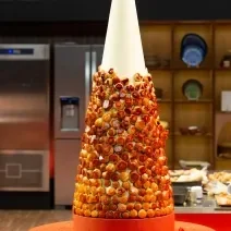 Fotografia em tons de caramelo com uma torre de choux com creme de confeiteiro com toque de laranja.