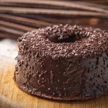 Foto da receita de Bolo de Chocolate. Observa-se um bolo com furo central e cobertura de brigadeiro.