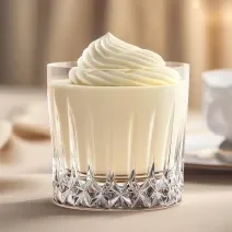 Fotografia de um copo de vidro com mousse de leite ninho e chantilly por cima.