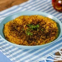 Fotografia em tons de azul com um prato azul ao centro. Em cima do prato existe uma receita de batata-doce rosti recheada com carne desfiada