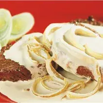 foto tirada de uma prato redondo e vermelho com dois bifes, creme por cima e cebolas
