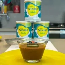 Fotografia em tons de amarelo com um potinho de vidro ao centro. Dentro do pote existe uma receita de mousse de chocolate com Ninho Adulto e chia