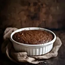 Fotografia de uma forma branca com bolo de chocolate sem glúten sobre uma mesa de madeira escura.