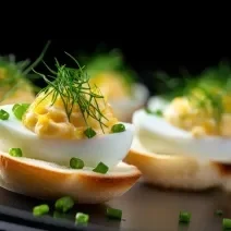 Fotografia de algumas unidades de canapés preparados com ovos de codorna e creme de leite com cebolinha por cima.