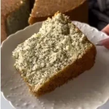 Fotografia de uma fatia grande de bolo de chia com limão sobre um prato branco.