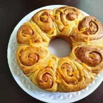 Foto da Receita de Pão de Rosas. Observa-se um pão com formato de rosas brilhante.