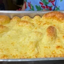 Fotografia de uma forma de alumínio retangular com o pão de queijo montanha russa preenchendo todo o recipiente.