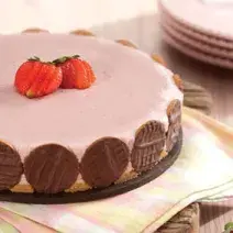 fotografia em tons de rosa e marrom tirada de uma torta de morango com biscoitos de chocolates em volta