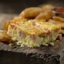 Fotografia de uma torta de panqueca recheada cortada em pedaços, sobre uma tábua de madeira.