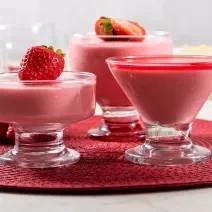 Receita de Nuvem de Morango, fácil e deliciosa, feita com NESTLÉ Creme de Leite, Leite MOÇA, Leite Líquido NINHO Forti+ Integral, coco ralado, Leite NINHO em Pó Integral e morangos frescos, servido em taças com morangos decorando