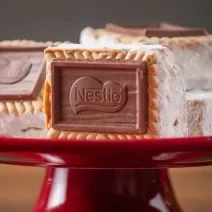 Fotografia de quatro unidades de palha italiana choco biscuit passadas no leite em pó. tem duas unidades no fundo, um por cima da outra, uma ao lado, e a palha italiana da frente está apoiada no centro da foto, todas estão sobre um apoio vermelho.