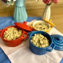 Fotografia em tons de rosa e azul com três panelinhas ao centro. Dentro de cada panelinha existe uma receita de arroz cremoso com ASCENDA