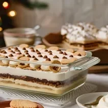 Foto da receita de pavê de natal, servido em uma travessa, em camadas de creme e biscoitos, servido em uma mesa decorada para o natal