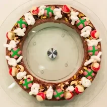 Foto da Receita de Guirlanda de Chocolate diferente e deliciosa feita com uma base de chocolate, bolas de natal bombons, laço de marshmallow e bombons fudge presentes de natal