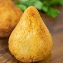 Fotografia de uma coxinha de jaca sobre uma tábua de madeira.