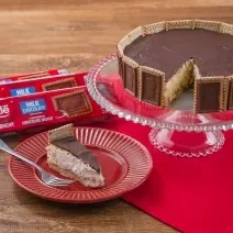 Fotografia em tons de vermelho com uma torta holandesa ao centro feita com Biscoito Choco Biscuit. Ao fundo existe três pacotes de biscoito Choco Biscuit NESTLÉ