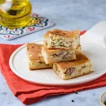 Fotografia mostra pedaços de torta de sardinha sobre um prato branco.