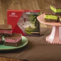 Receita de Brownie Wicked, servidos em pedaços de brownie de chocolate, metade com creme rosa e metade com creme verde, todos cobertos com Chocolate. Alguns em prato verde e outros em um prato rosa alto. No meio há uma caixa de KitKat Wicked.