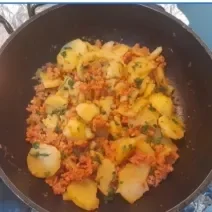 Fotografia de uma panela preta funda com batatas e calabresa moída.