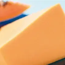 Fotografia em tons de laranja e azul vista de frente, um prato azul quadrado contém pedaços de mamão.