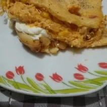 Fotografia de um pedaço de torta de frango com requeijão sobre um prato branco com desenhos.