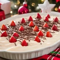 Receita de um doce cremoso com morangos picados, coberto com chocolate por cima, servido em uma travessa sobre uma mesa decorada para o natal