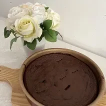 Fotografia de uma forma redonda antianderente com um brownie de chocolate e batata doce. A forma está sobre uma tábua de madeira.