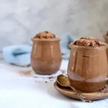 Foto da receita de Mousse de Chocolate Zero Lactose. Observa-se três potes de vidro transparentes com a mousse de chocolate dentro.