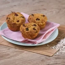 Foto da receita de Muffin de Maçã e Manga. Observa-se 3 muffins em cima de um guardanapo rosa e um prato azul.