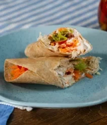 Fotografia mostra um lanche feito com wrap recheado com legumes e frango.