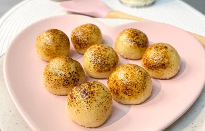 Foto da receita de brigadeiro brulle da andressa ventura, servido em um prato rosa em formato de coração, numa mesa onde há uma lata de leite moça, um pequeno vaso de flores