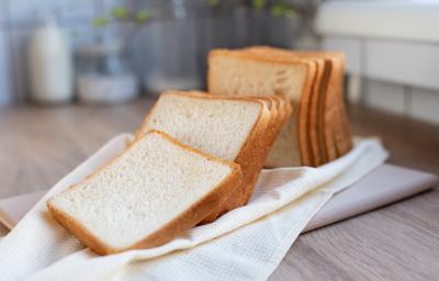 Foto da receita de Pão de Liquidificador sem Sovar. Observa-se um pão cortado em fatias sobre um pano de prato off white.