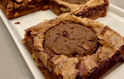 Fotografia mostra um brownie de chocolate com um cookie de chocolate em cima.